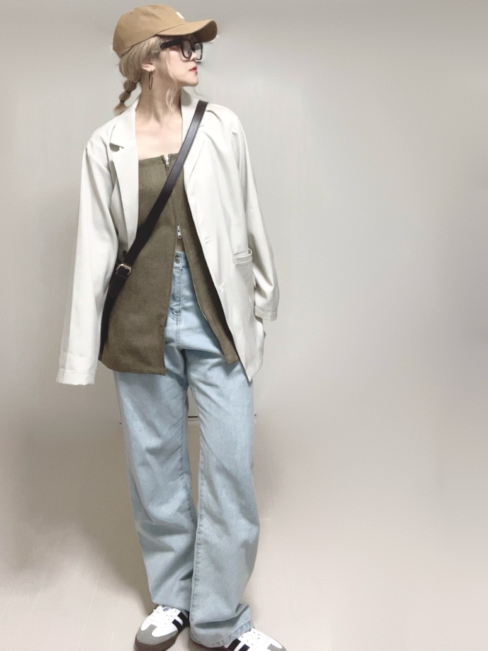 ホワイト系のテーラードジャケット、ブラウン系のベスト、ブルー系のデニムパンツを着用したレディースの春コーディネートの3枚目の写真