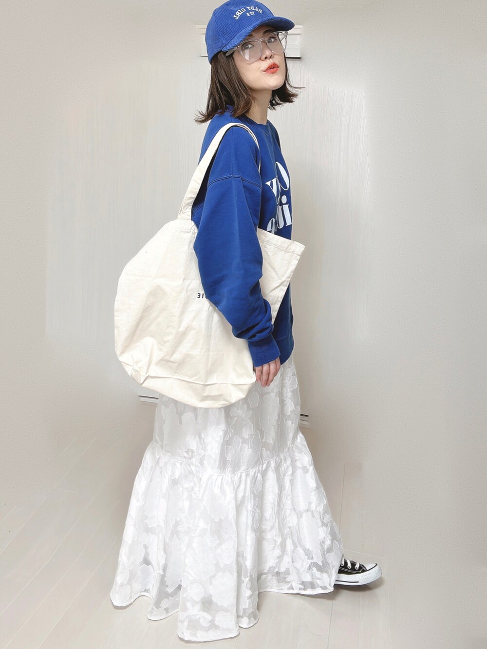 ブルー系のスウェット、ホワイト系のトートバッグ、ホワイト系のスカートを着用したレディースの春コーディネートの2枚目の写真