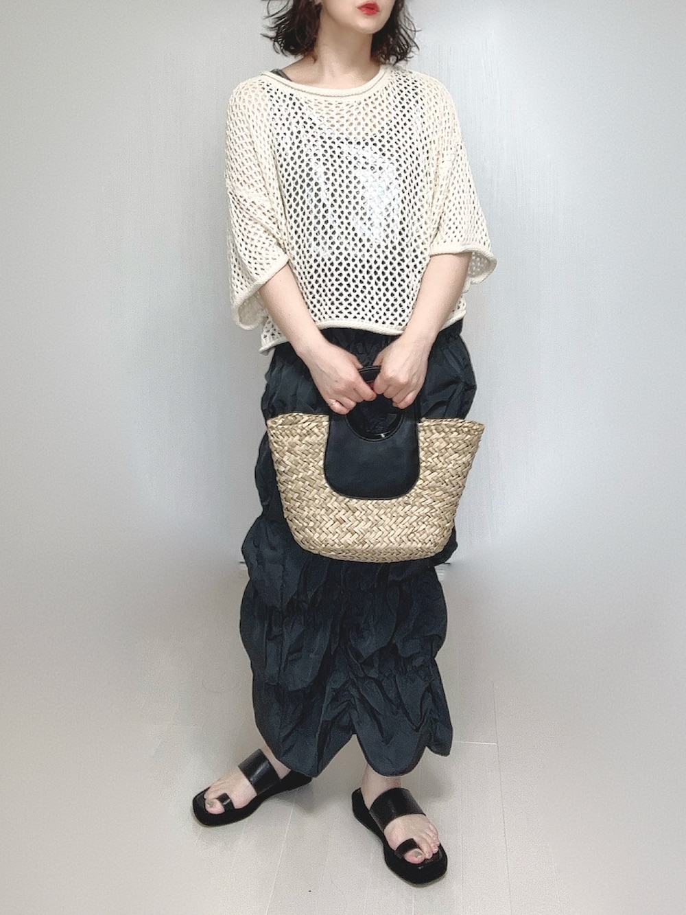 グレー系のスカート、シルバー系のタンクトップ、ベージュ系のニット/セーターを着用したレディースの春コーディネートの4枚目の写真