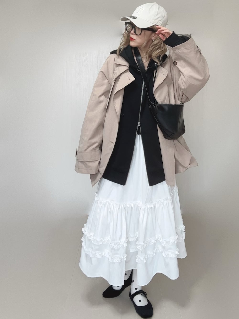 ブラック系のパーカー、ホワイト系のスカート、ベージュ系のトレンチコートを着用したレディースの春コーディネートの2枚目の写真