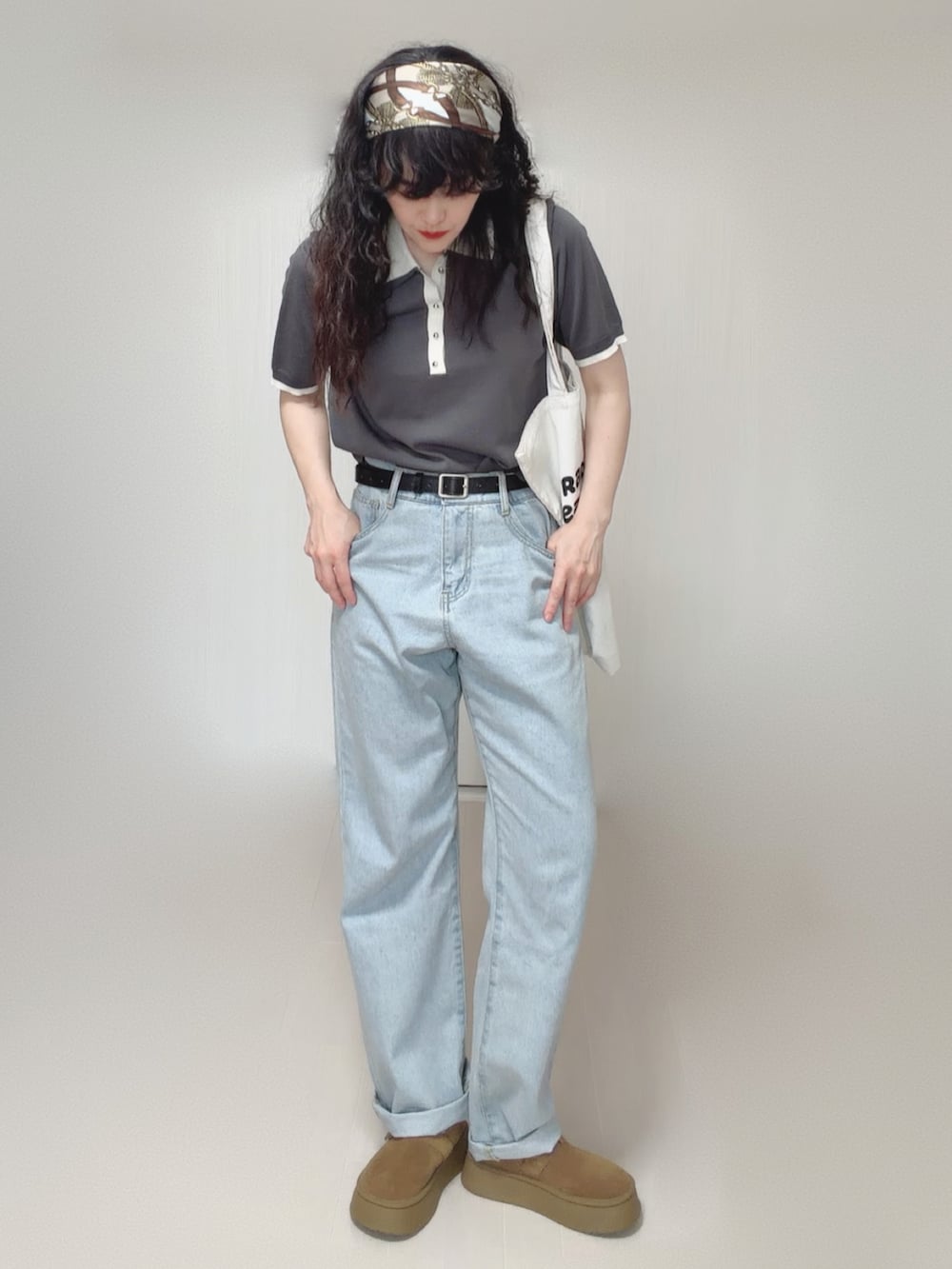 グレー系のポロシャツ、ブルー系のデニムパンツ、ホワイト系のトートバッグを着用したレディースの夏コーディネートの2枚目の写真