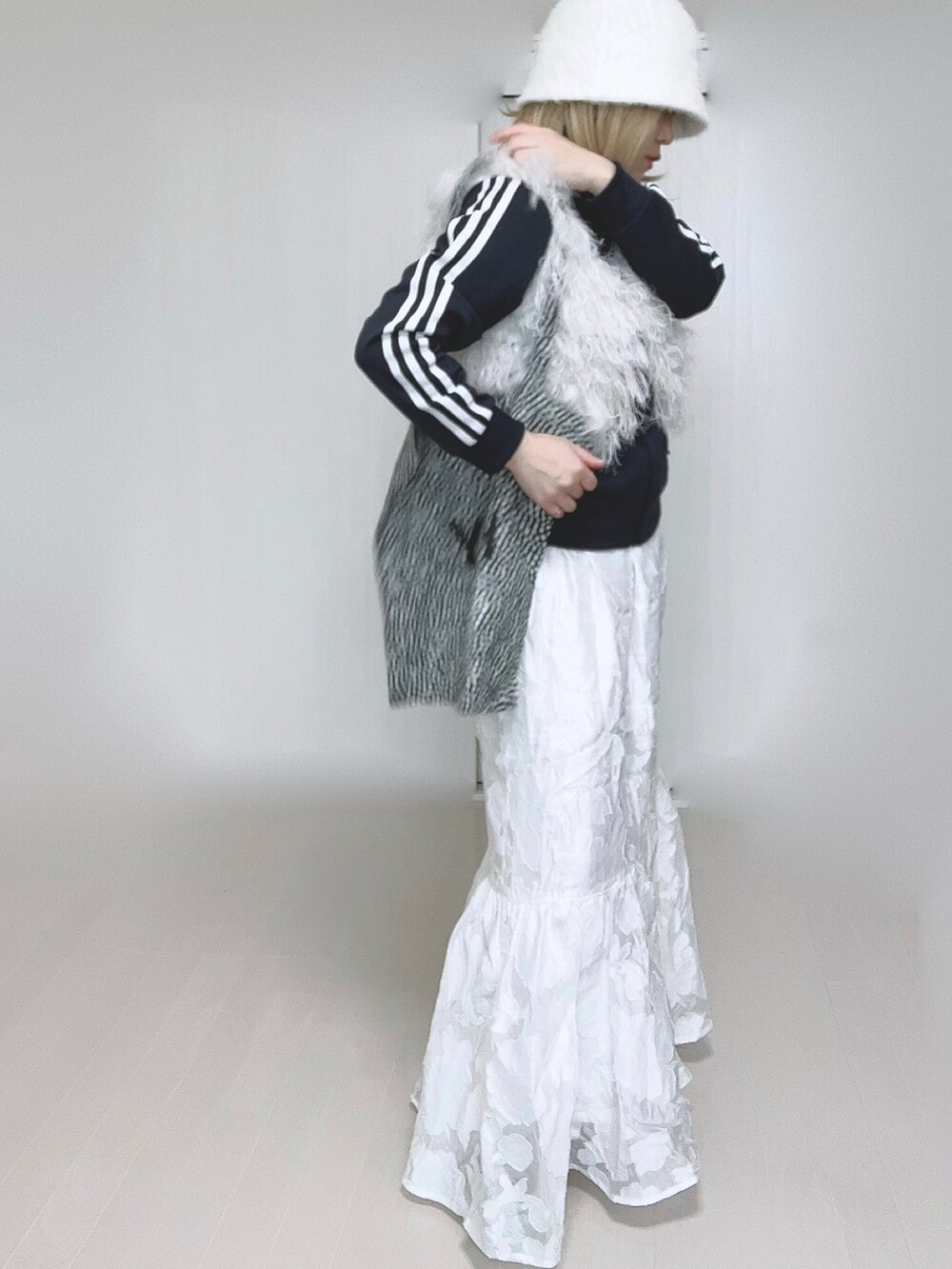 ホワイト系のベスト、ブルー系のナイロンジャケット、ホワイト系のスカートを着用したレディースの冬コーディネートの3枚目の写真