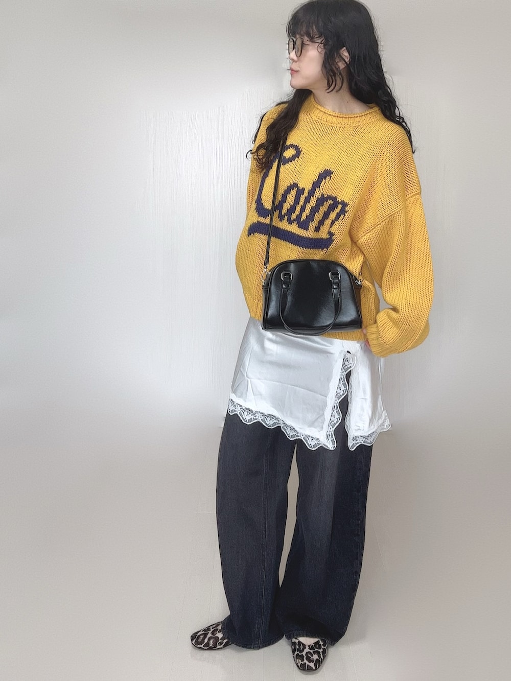 イエロー系のニット/セーター、ブラック系のデニムパンツ、ホワイト系のワンピースを着用したレディースの春コーディネートの4枚目の写真