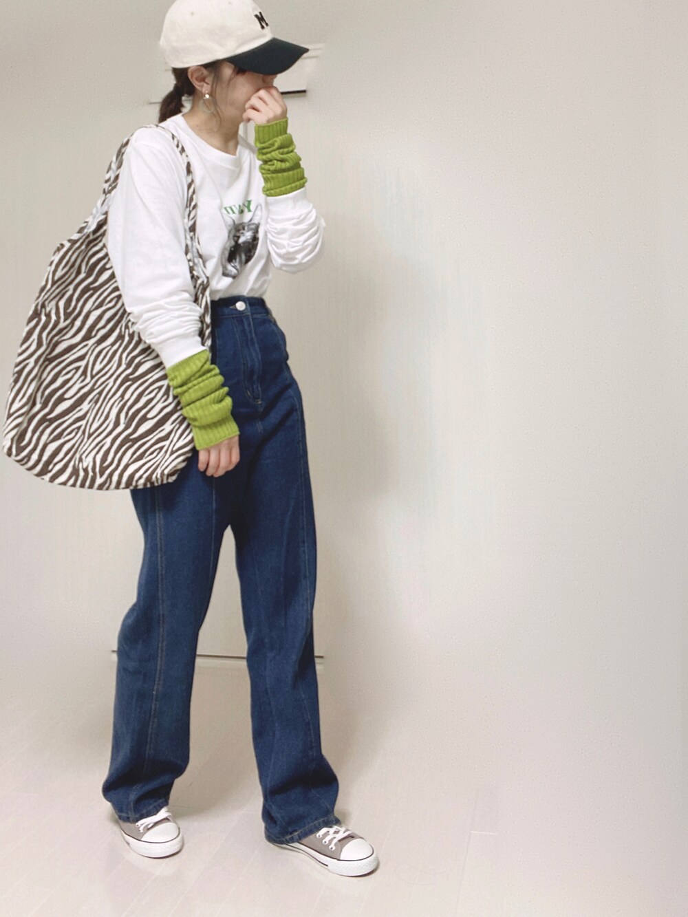 ホワイト系のTシャツ/カットソー、ブルー系のデニムパンツ、グリーン系のアームカバーを着用したレディースの秋コーディネートの4枚目の写真