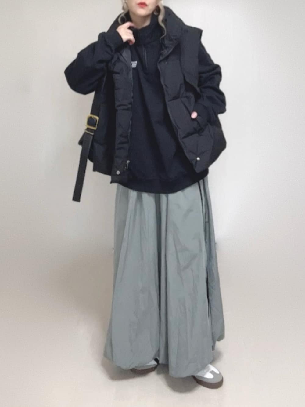 ブラック系のダウンベスト、ブラック系のスウェット、ブルー系のキャップを着用したレディースの秋コーディネートの3枚目の写真