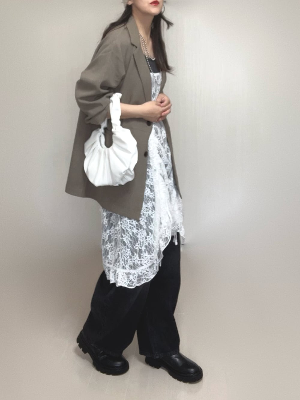 ベージュ系のテーラードジャケット、ホワイト系のチュニック、ブラック系のブーツを着用したレディースの夏コーディネートの4枚目の写真