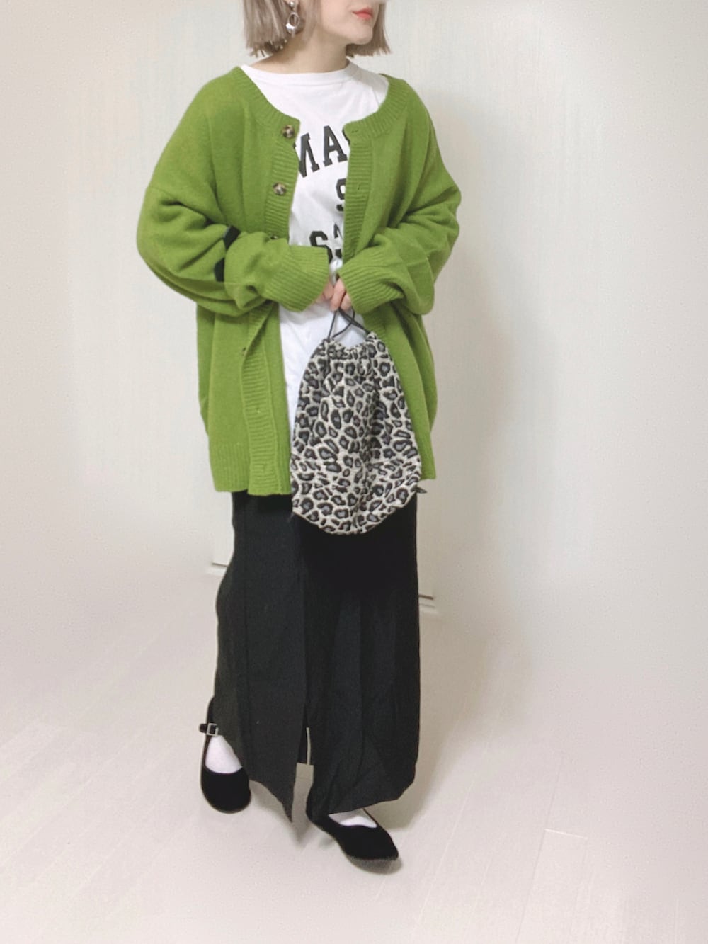 グリーン系のカーディガン/ボレロ、ホワイト系のTシャツ/カットソー、ブラック系のスカートを着用したレディースの秋コーディネートの2枚目の写真