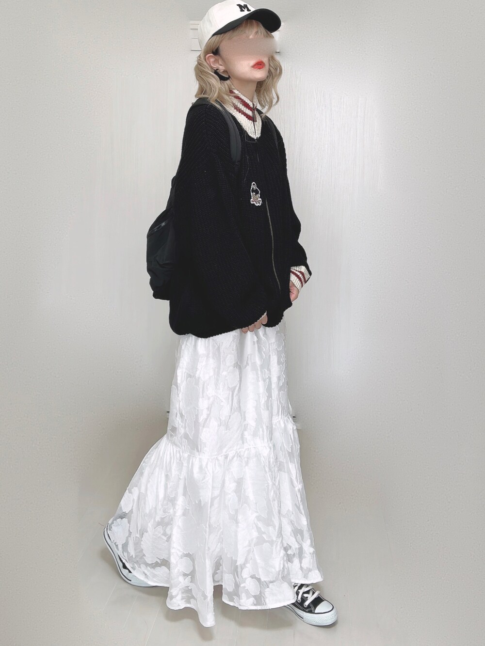 ブラック系のニット/セーター、ブラック系のバックパック/リュック、ホワイト系のスカートを着用したレディースの秋コーディネートの4枚目の写真