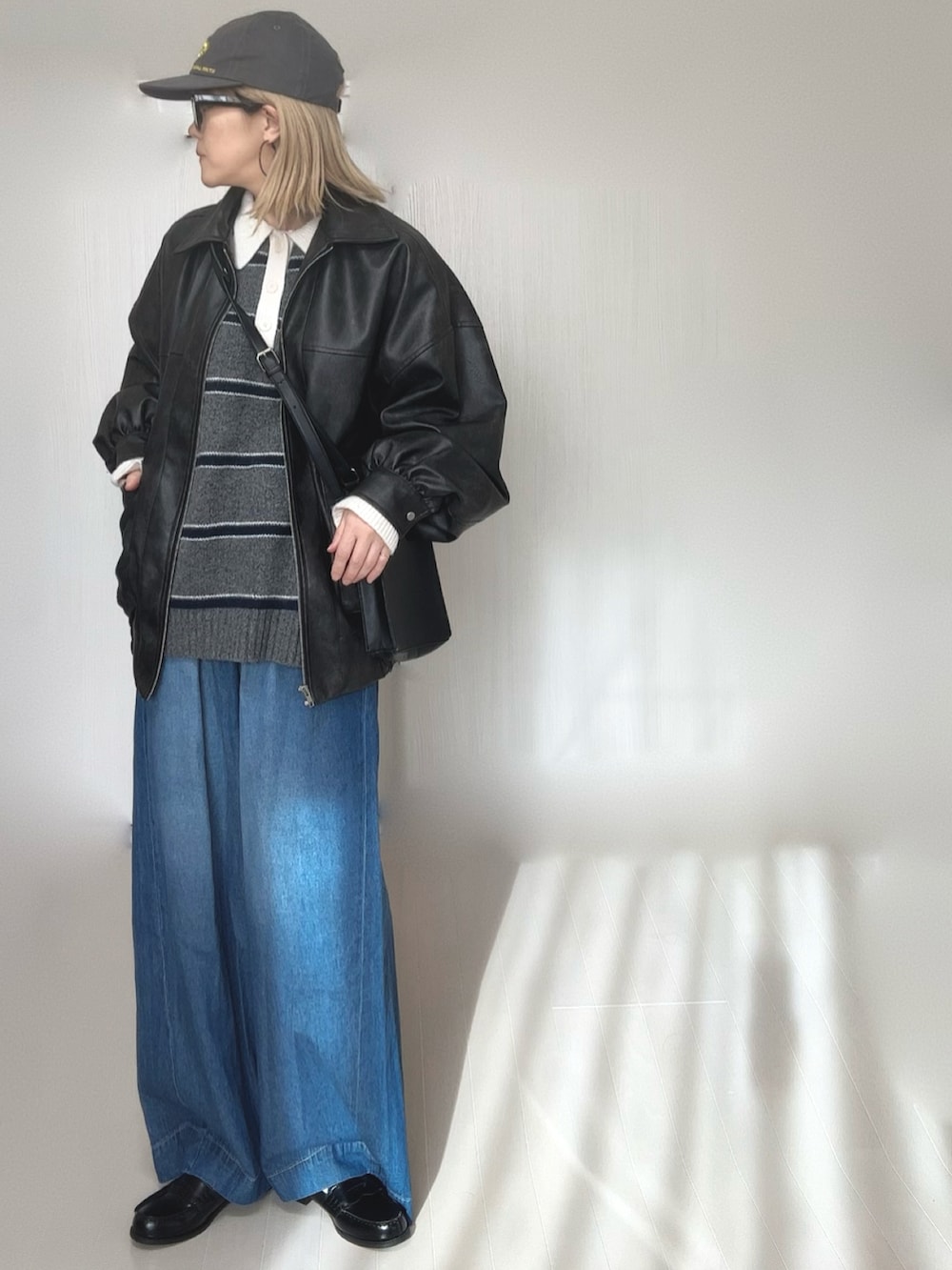 グレー系のニット/セーター、ブラック系のブルゾン、ブルー系のデニムパンツを着用したレディースの冬コーディネートの5枚目の写真