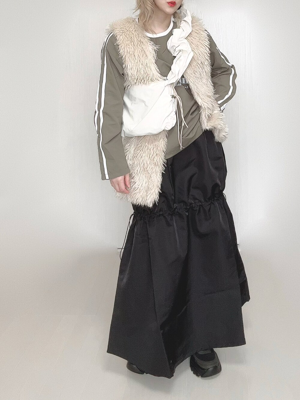 ホワイト系のショルダーバッグ、ホワイト系のベスト、ブラック系のスカートを着用したレディースの春コーディネートの2枚目の写真