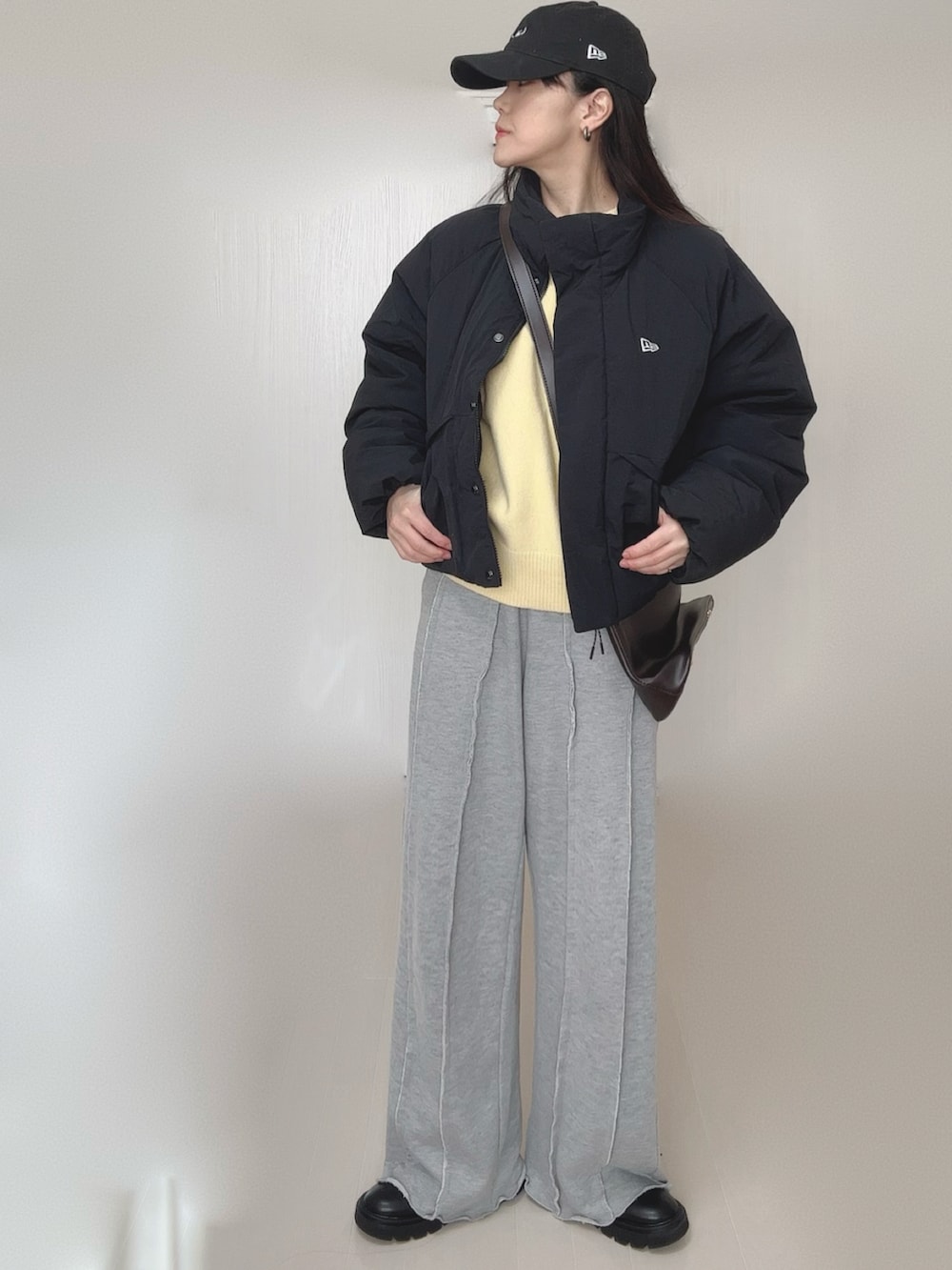 イエロー系のニット/セーター、グレー系のスウェットパンツ、ブラック系のブーツを着用したレディースの冬コーディネートの2枚目の写真