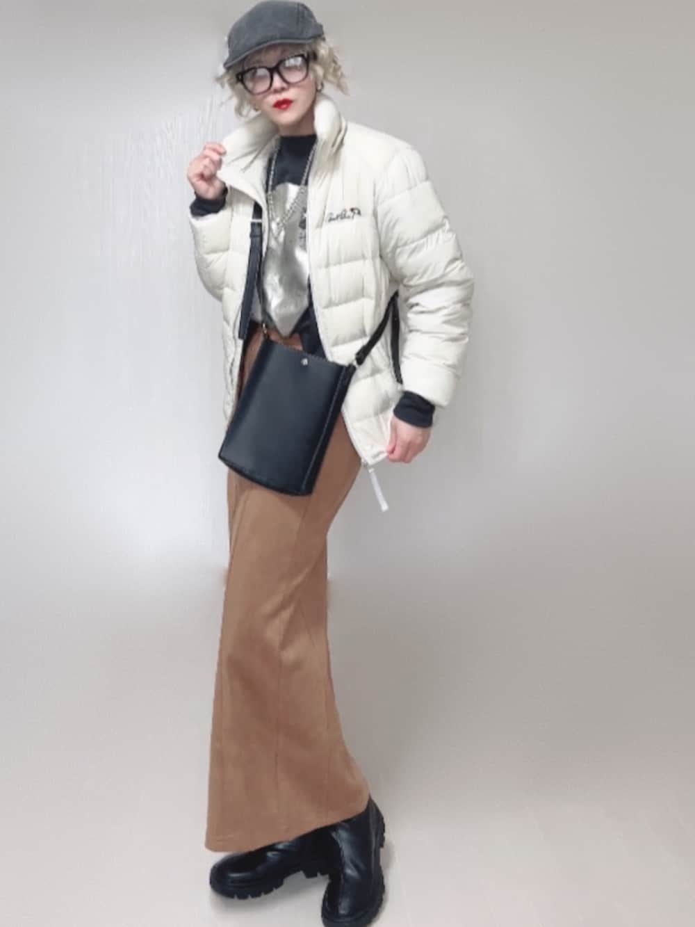 ブラック系のブーツ、ホワイト系のダウンジャケット/コート、ブラック系のショルダーバッグを着用したレディースの秋コーディネートの3枚目の写真