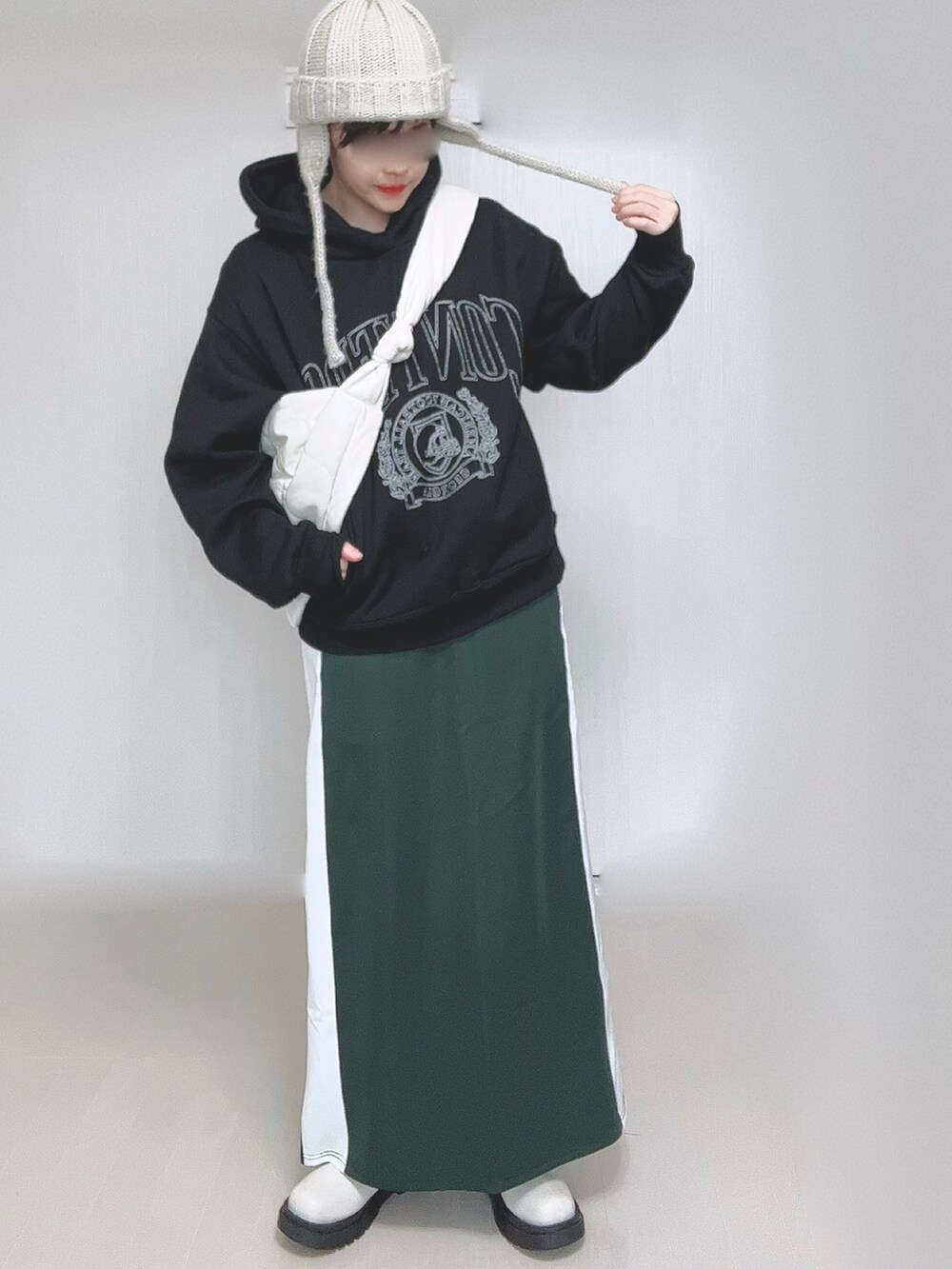 ブラック系のパーカー、ホワイト系のショルダーバッグ、グリーン系のスカートを着用したレディースの冬コーディネートの3枚目の写真