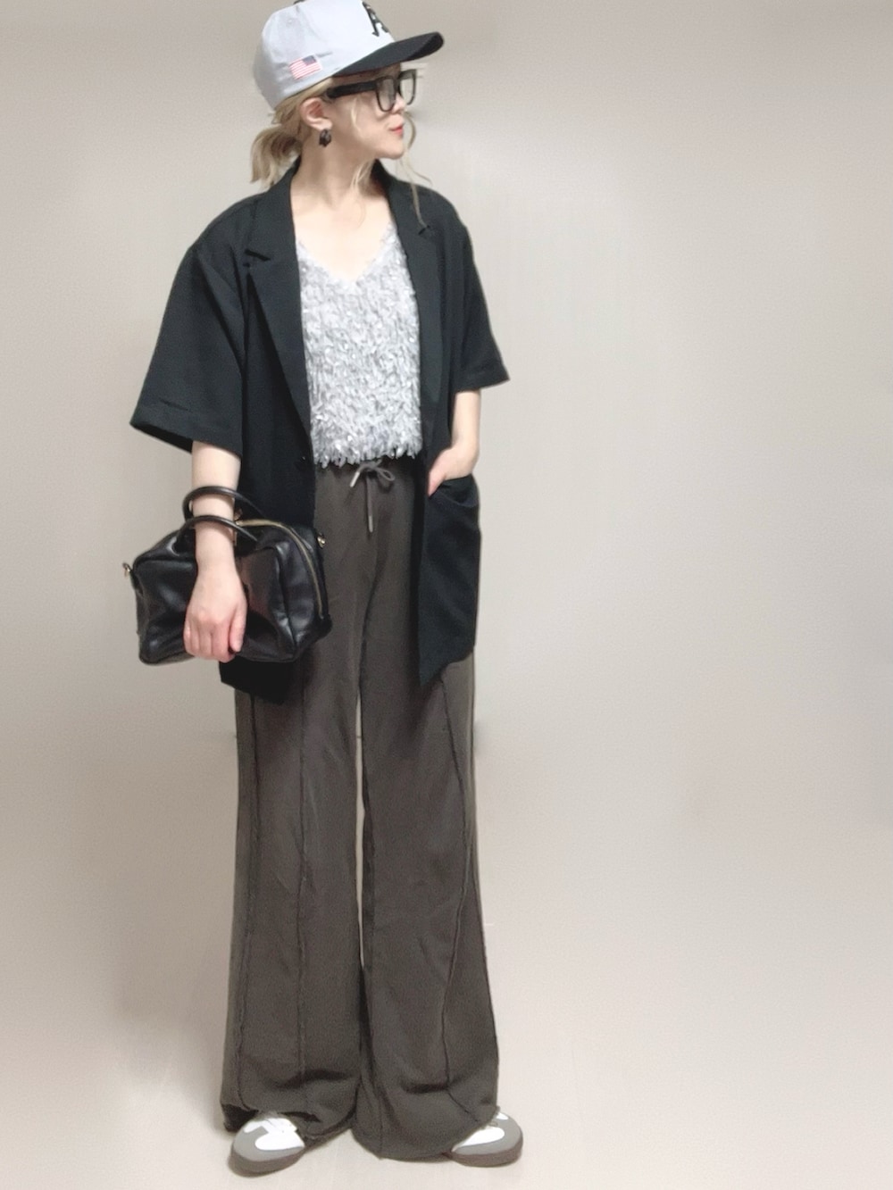 グレー系のベスト、ブラック系のテーラードジャケット、ブラック系のスウェットパンツを着用したレディースの夏コーディネートの5枚目の写真