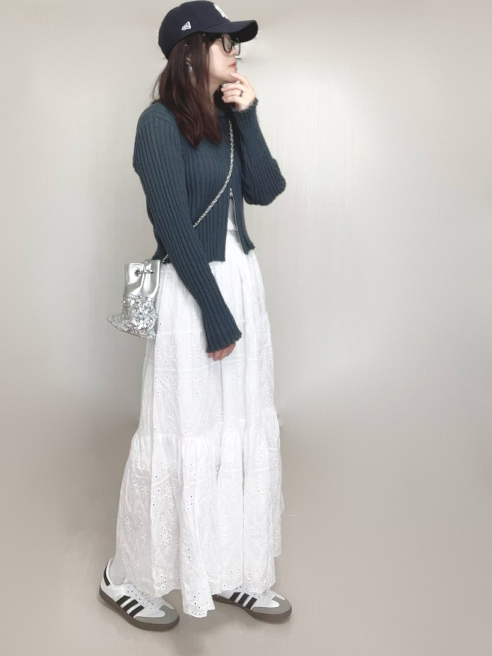 グレー系のカーディガン/ボレロ、シルバー系のショルダーバッグ、ホワイト系のスカートを着用したレディースの春コーディネートの2枚目の写真