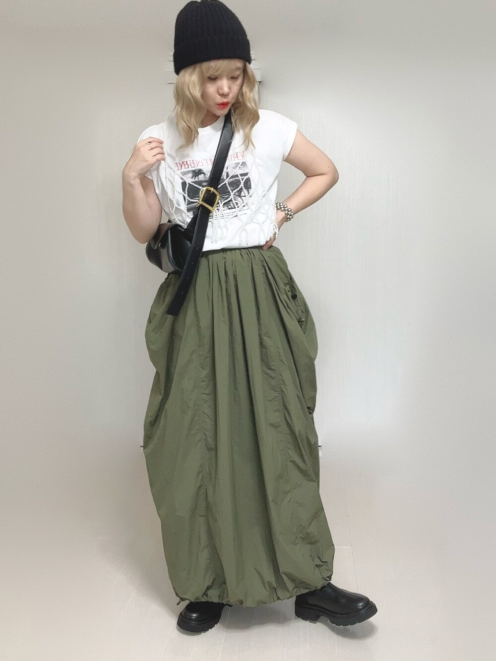 ブラック系のブーツ、グリーン系のスカート、ホワイト系のベストを着用したレディースの秋コーディネートの3枚目の写真