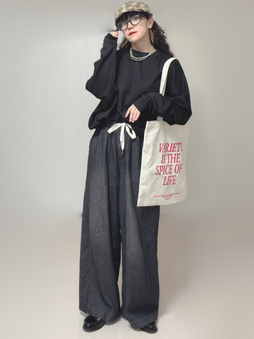 ブラック系のスウェット、ブラック系のデニムパンツ、ホワイト系のトートバッグを着用したレディースの春コーディネートの5枚目の写真