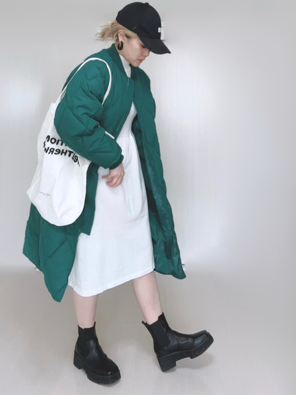 グリーン系のダウンジャケット/コート、ホワイト系のワンピース、ホワイト系のトートバッグを着用したレディースの冬コーディネートの4枚目の写真