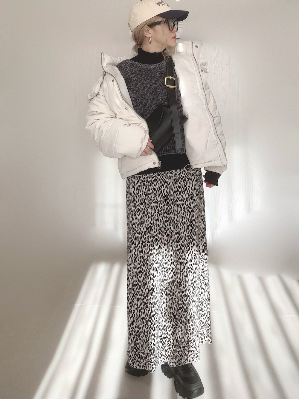 ブラック系のニット/セーター、ブラック系のTシャツ/カットソー、ホワイト系のダウンジャケット/コートを着用したレディースの冬コーディネートの2枚目の写真