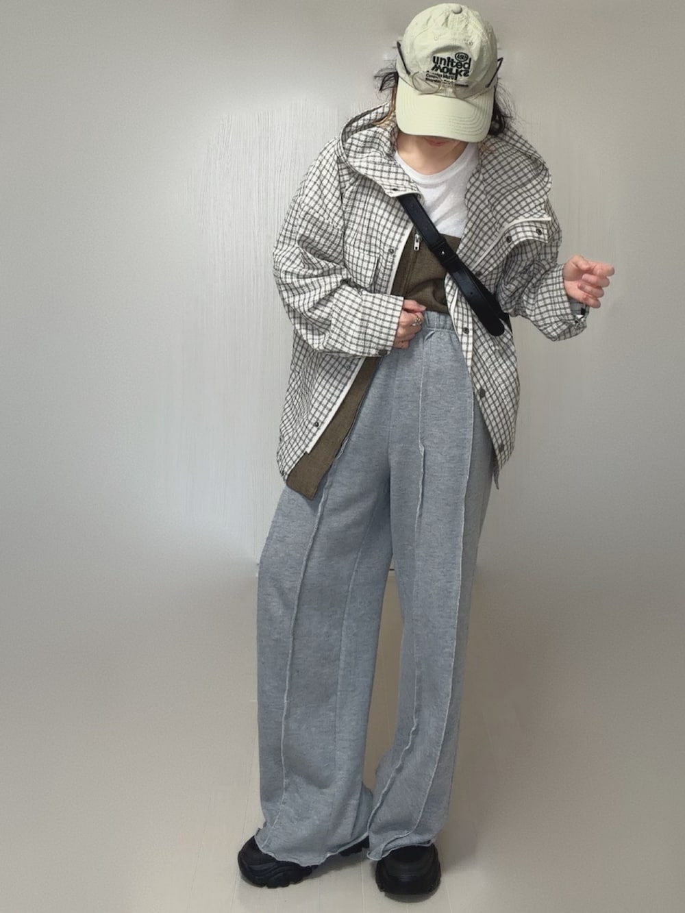 ホワイト系のパーカー、グレー系のスウェットパンツ、ブラウン系のベストを着用したレディースの春コーディネートの4枚目の写真