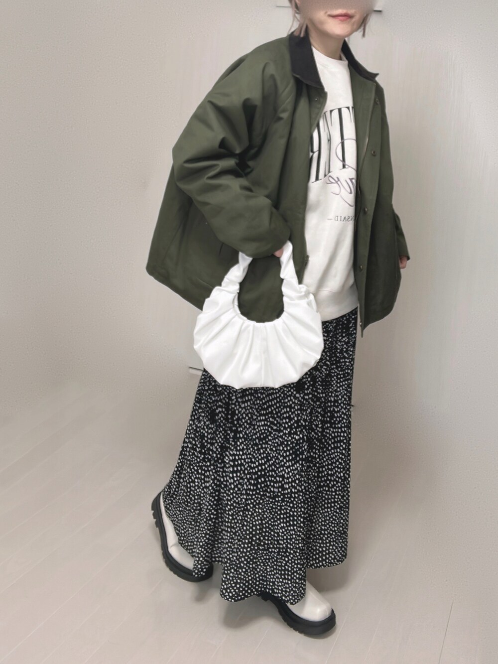 グリーン系のカバーオール、ブラック系のスカート、ホワイト系のブーツを着用したレディースの冬コーディネートの4枚目の写真