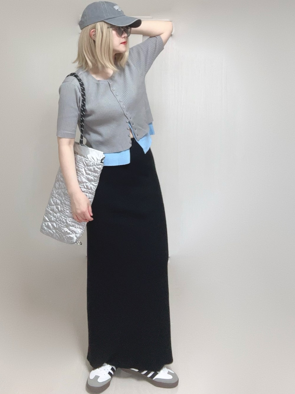 グレー系のニット/セーター、シルバー系のトートバッグ、ブラック系のスカートを着用したレディースの春コーディネートの2枚目の写真