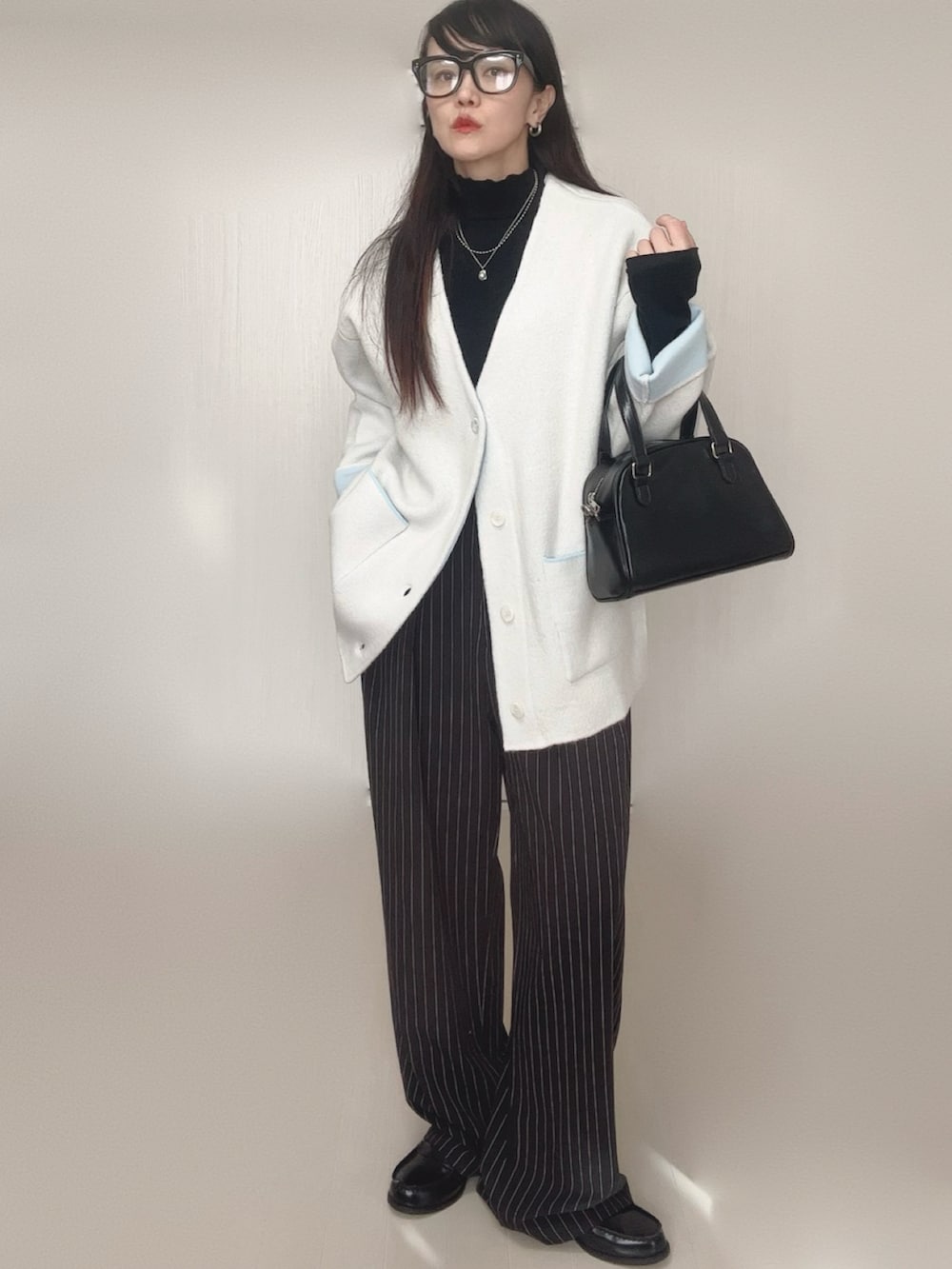 ホワイト系のカーディガン/ボレロ、ブラック系のTシャツ/カットソー、ブラック系のスラックスを着用したレディースの冬コーディネートの2枚目の写真