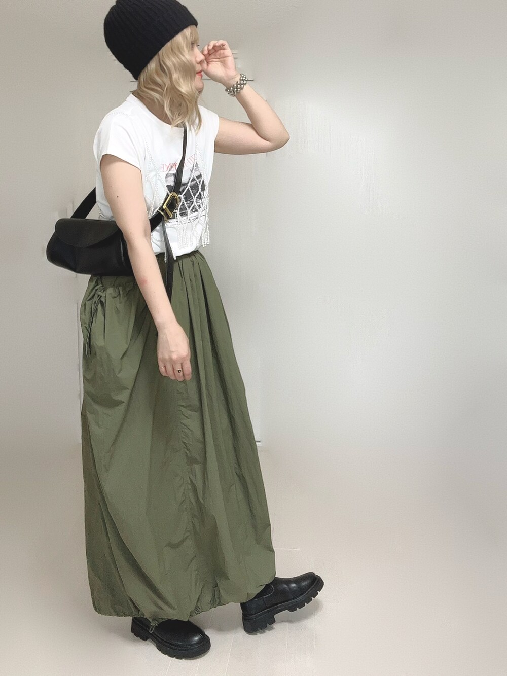 ブラック系のブーツ、グリーン系のスカート、ホワイト系のベストを着用したレディースの秋コーディネートの4枚目の写真