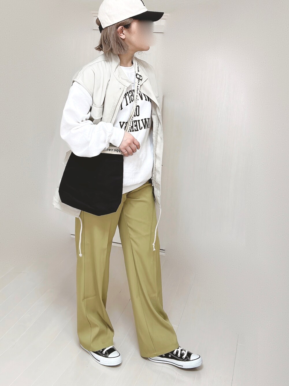 グリーン系のスラックス、ホワイト系のベスト、ホワイト系のスウェットを着用したレディースの春コーディネートの2枚目の写真