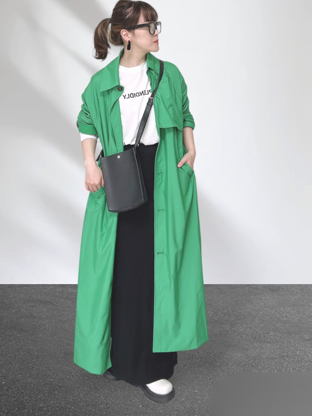 グリーン系のトレンチコート、ブラック系のショルダーバッグ、ブラック系のスカートを着用したレディースの秋コーディネートの2枚目の写真