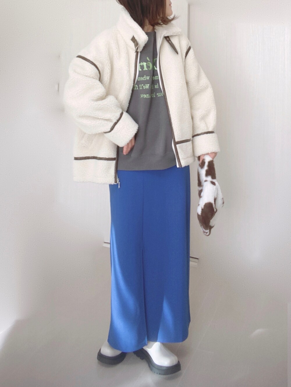 ホワイト系のブルゾン、グレー系のスウェット、ブルー系のスカートを着用したレディースの秋コーディネートの3枚目の写真