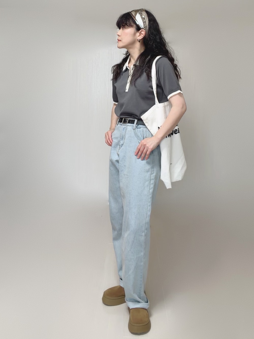 グレー系のポロシャツ、ブルー系のデニムパンツ、ホワイト系のトートバッグを着用したレディースの夏コーディネートの5枚目の写真