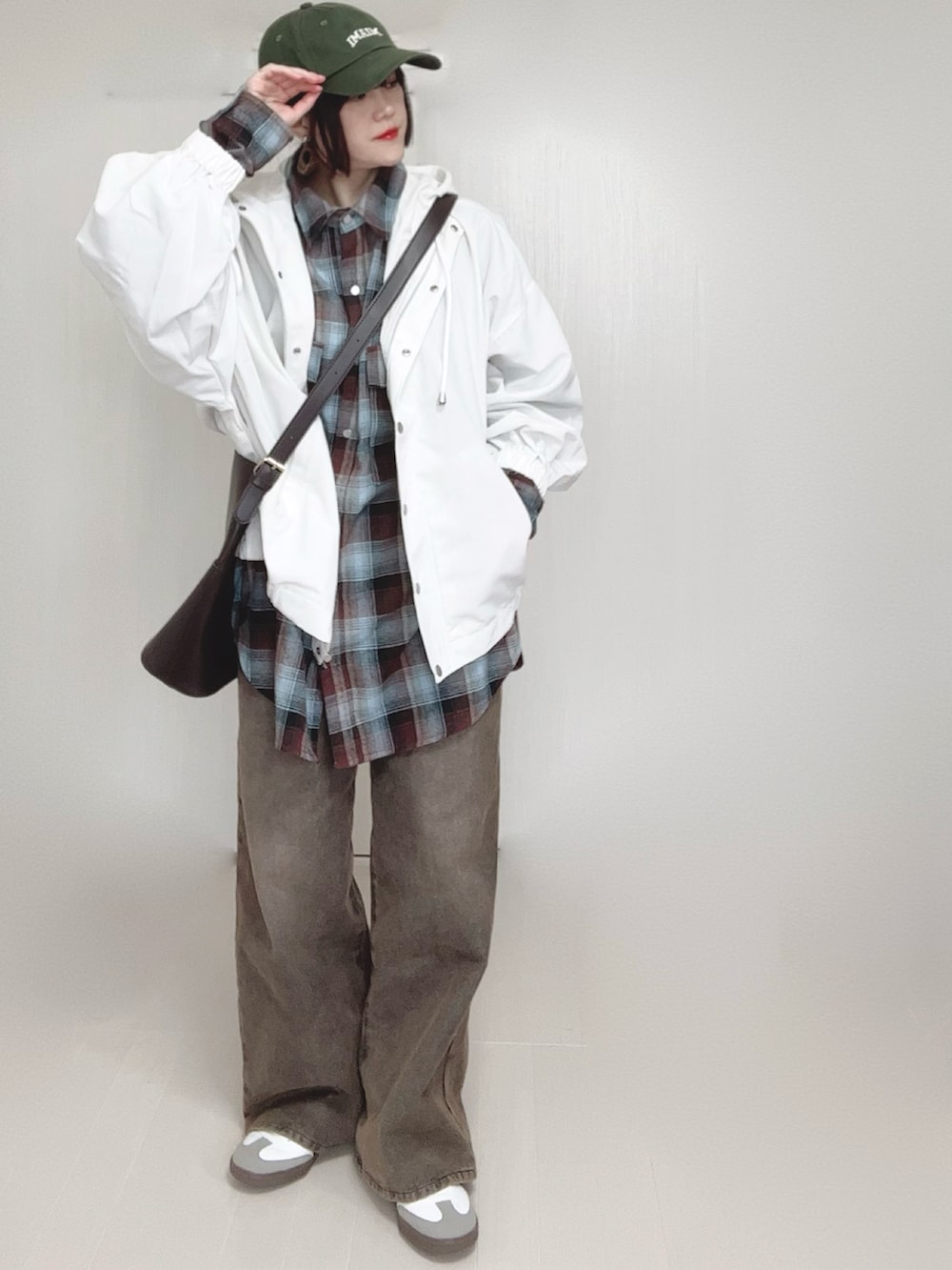 ホワイト系のマウンテンパーカー、ブラウン系のシャツ/ブラウス、ブラック系のデニムパンツを着用したレディースの春コーディネートの4枚目の写真