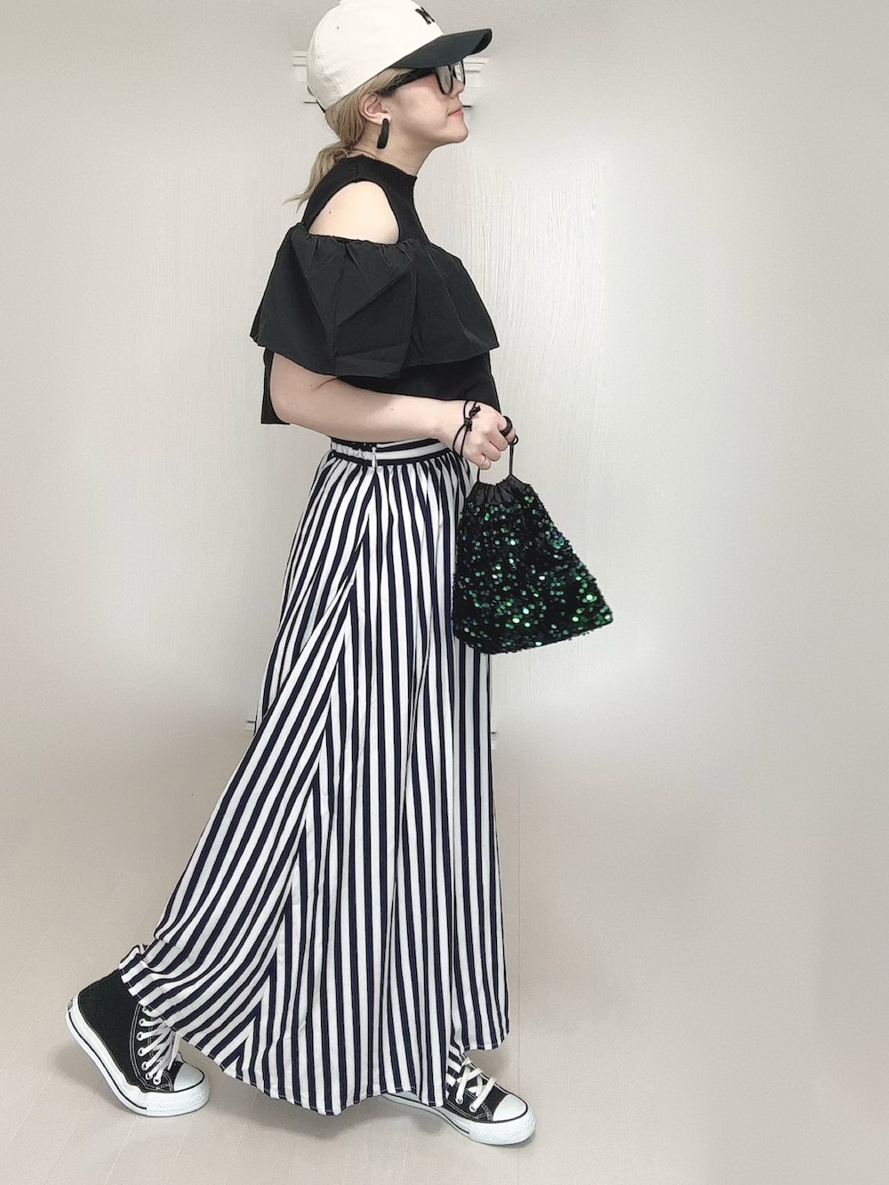 ブルー系のスカート、ブラック系のスニーカー、ブラック系のキャップを着用したレディースの春コーディネートの3枚目の写真