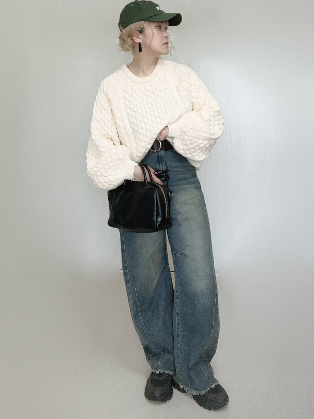 ブルー系のデニムパンツ、ホワイト系のニット/セーター、ブラック系のボストンバッグを着用したレディースの秋コーディネートの3枚目の写真