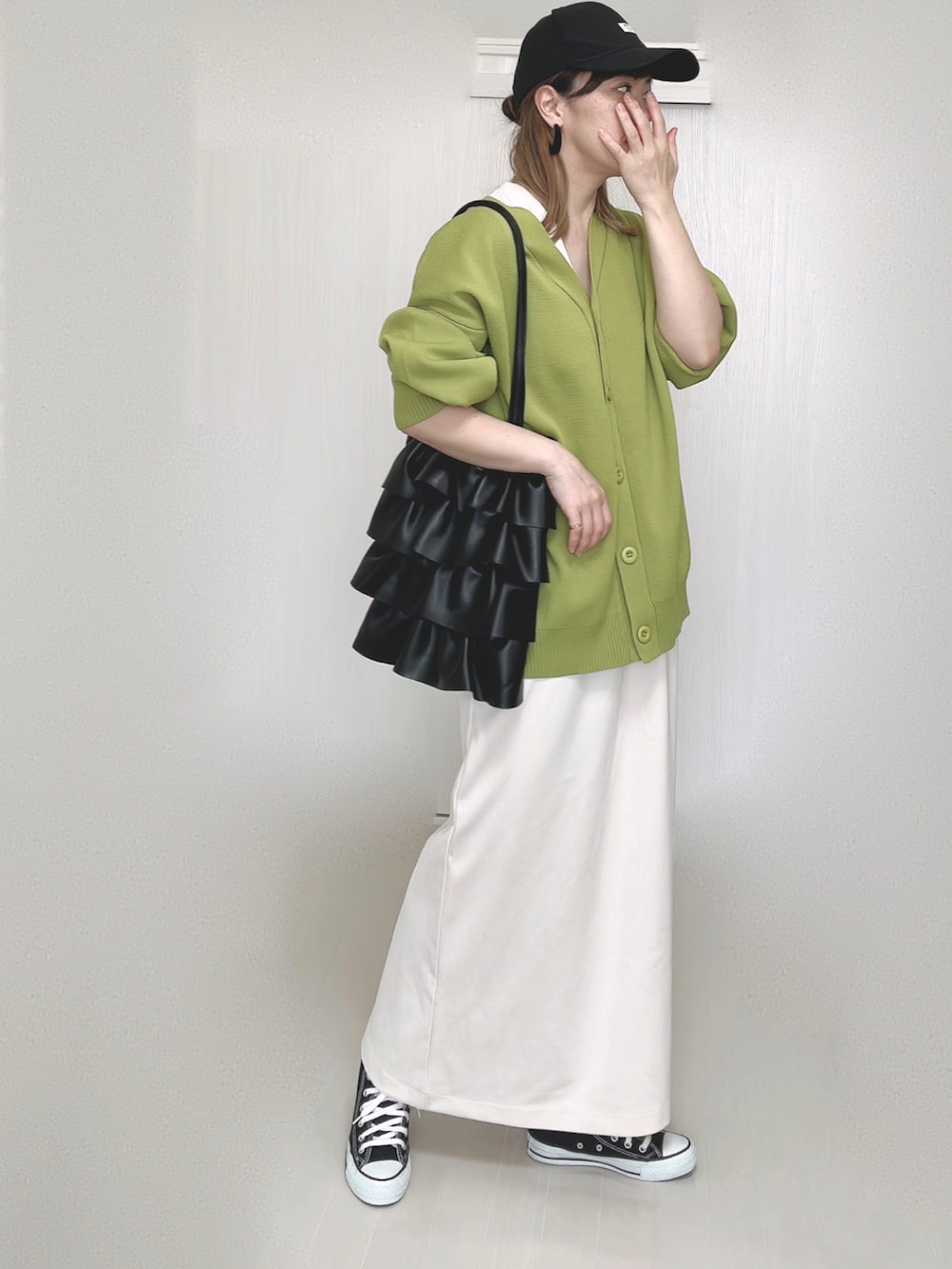 グリーン系のカーディガン/ボレロ、ホワイト系のワンピース、ブラック系のスニーカーを着用したレディースの秋コーディネートの2枚目の写真
