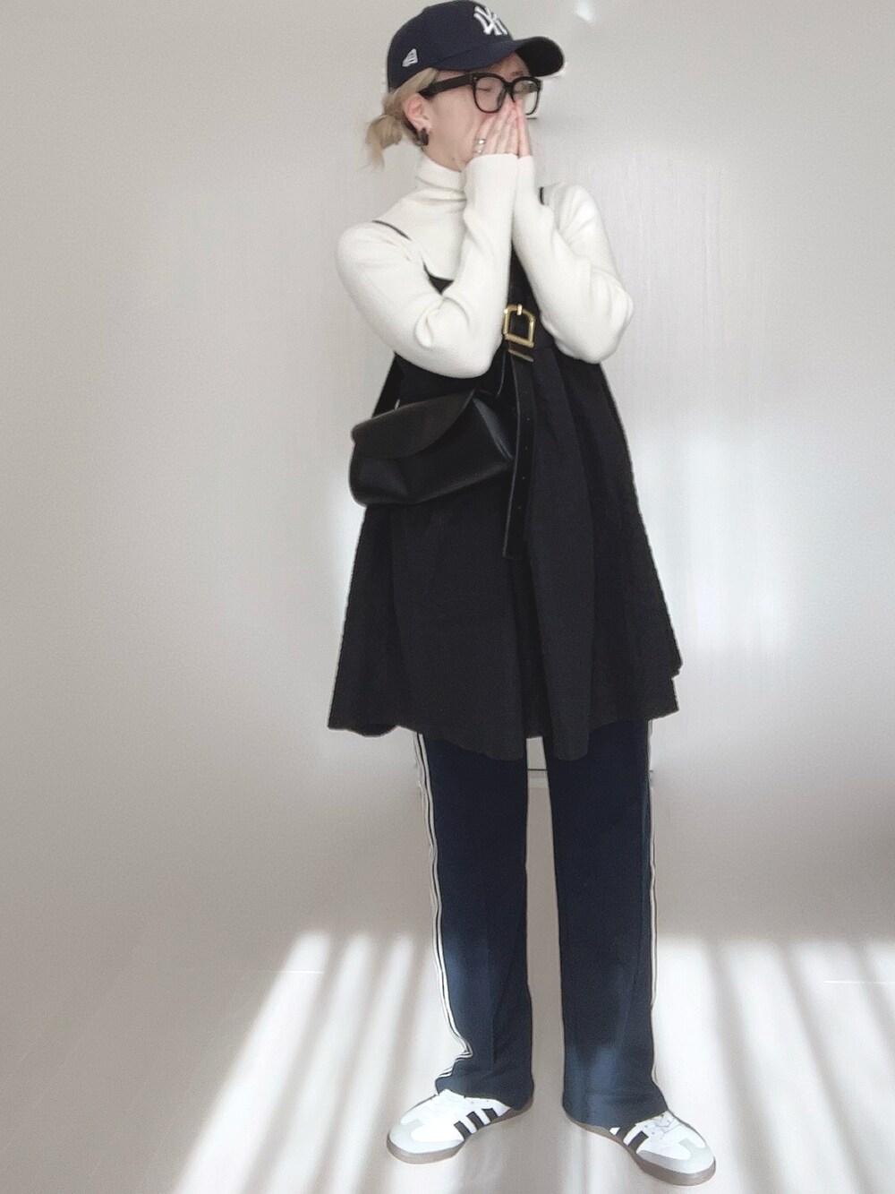 ブルー系のスウェットパンツ、ホワイト系のニット/セーター、ブラック系のワンピースを着用したレディースの春コーディネートの3枚目の写真