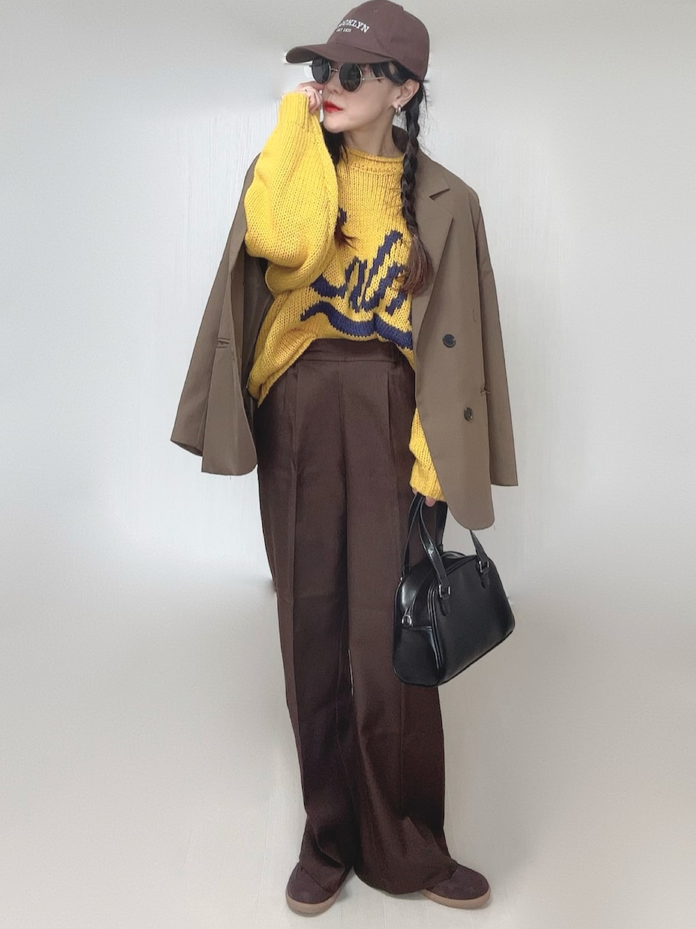イエロー系のニット/セーター、ブラウン系のテーラードジャケット、ブラウン系のその他パンツを着用したレディースの冬コーディネートの4枚目の写真