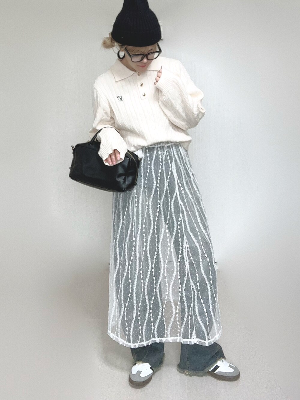 ホワイト系のニット/セーター、ブルー系のデニムパンツ、ホワイト系のスカートを着用したレディースの冬コーディネートの2枚目の写真