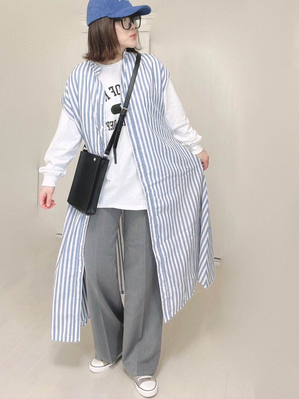 ブルー系のシャツワンピース、ホワイト系のTシャツ/カットソー、ブラック系のショルダーバッグを着用したレディースの春コーディネートの5枚目の写真