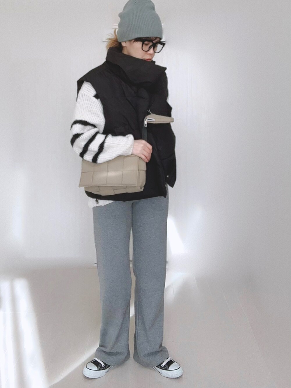 ブラック系のダウンベスト、ホワイト系のニット/セーター、グレー系のその他パンツを着用したレディースの冬コーディネートの4枚目の写真