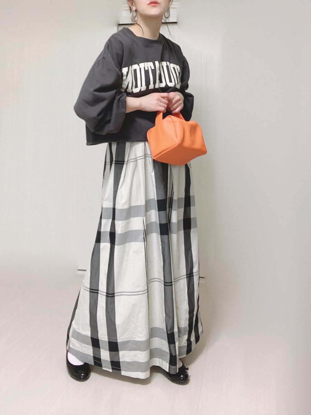 ホワイト系のスカート、オレンジ系のショルダーバッグ、ブラック系のバレエシューズを着用したレディースの春コーディネートの2枚目の写真