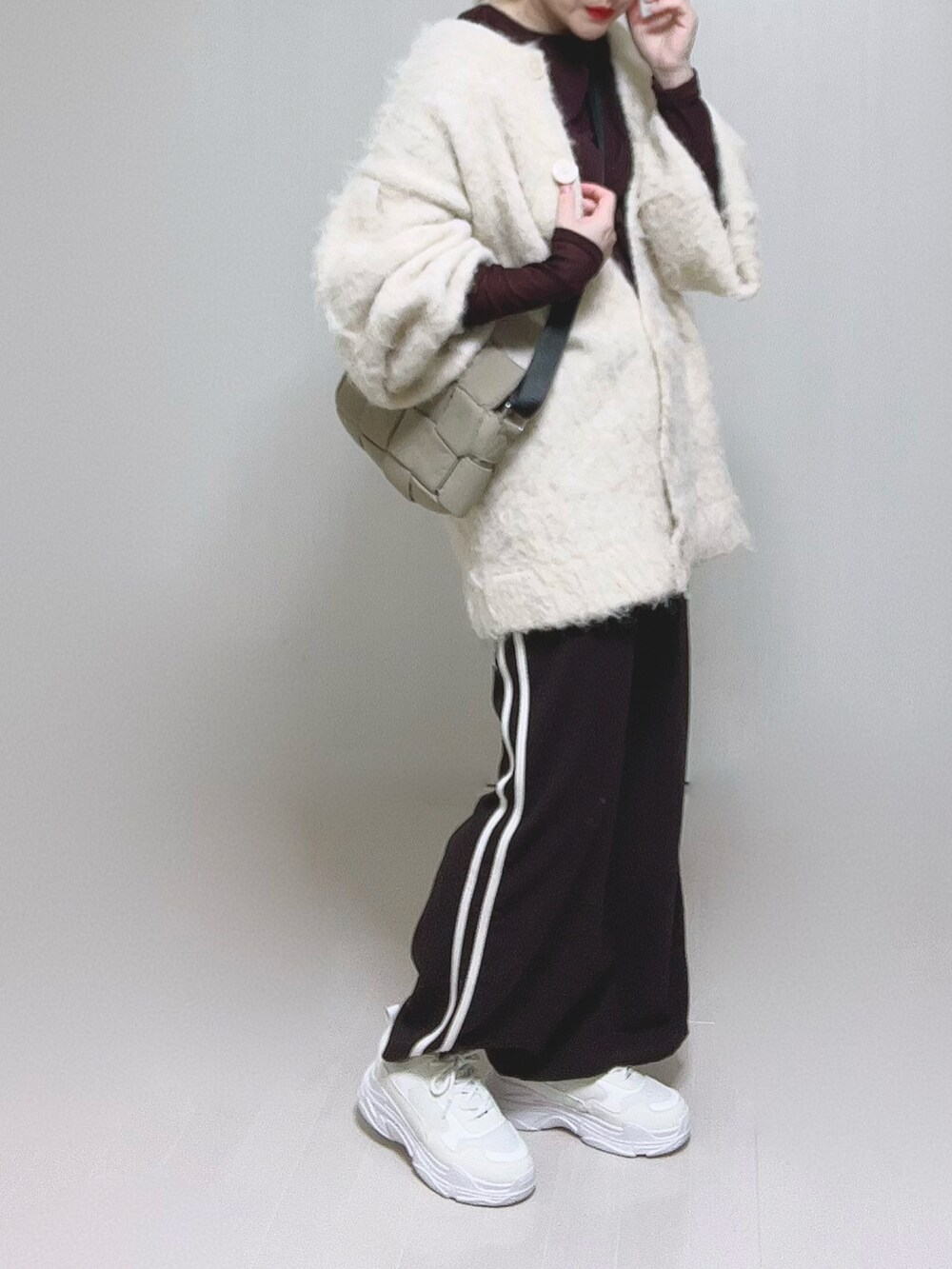 ベージュ系のカーディガン/ボレロ、ブラウン系のTシャツ/カットソー、ホワイト系のスニーカーを着用したレディースの冬コーディネートの3枚目の写真