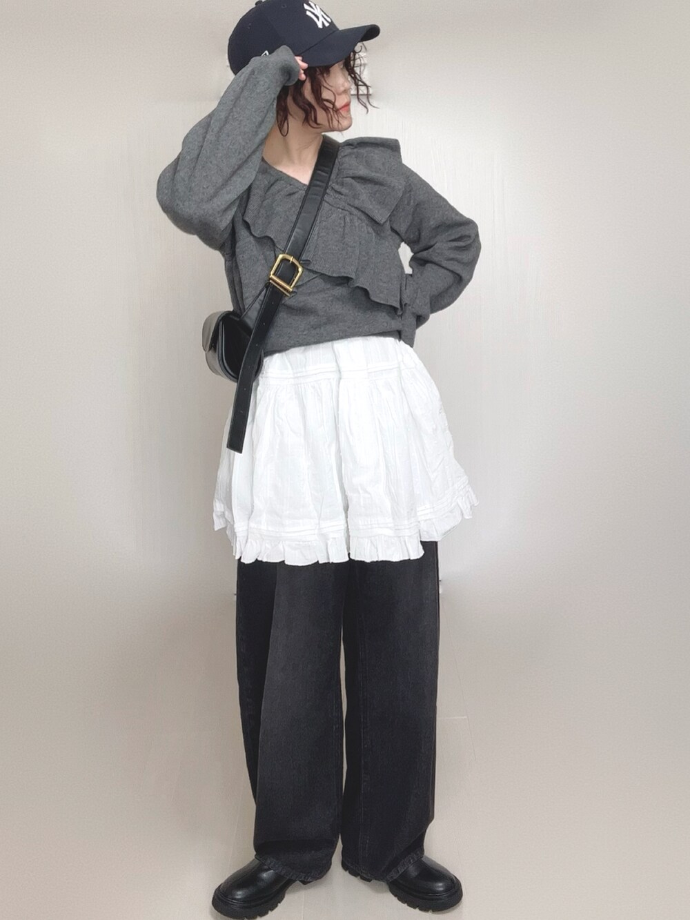 グレー系のニット/セーター、ブラック系のデニムパンツ、ホワイト系のスカートを着用したレディースの秋コーディネートの5枚目の写真