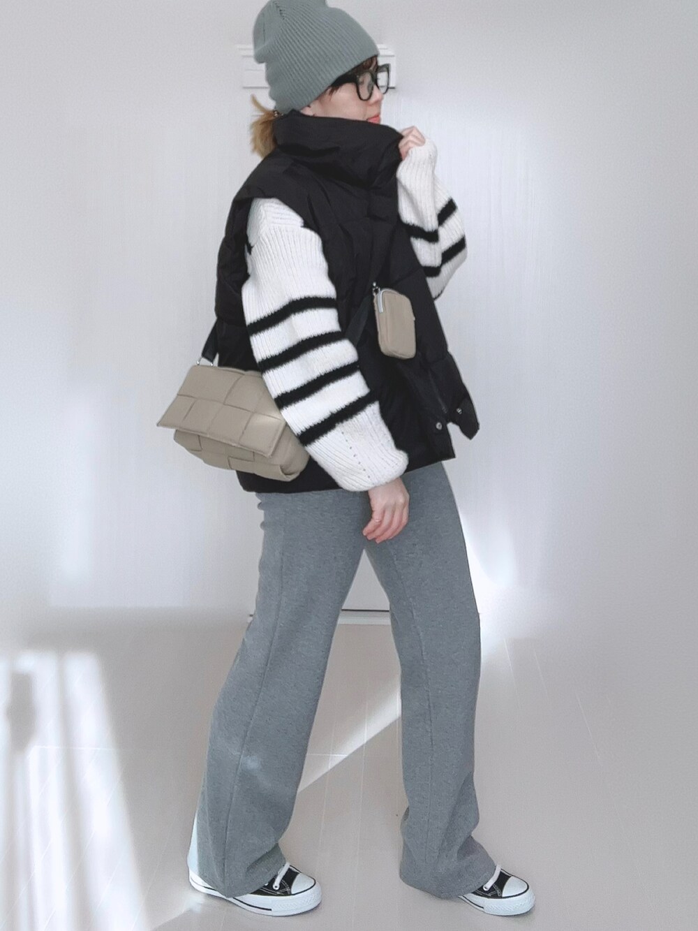 ブラック系のダウンベスト、ホワイト系のニット/セーター、グレー系のその他パンツを着用したレディースの冬コーディネートの3枚目の写真