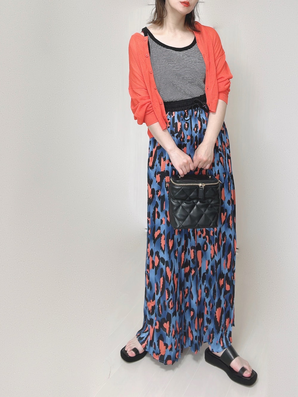 ブルー系のスカート、オレンジ系のカーディガン/ボレロ、ブラック系のタンクトップを着用したレディースの夏コーディネートの5枚目の写真