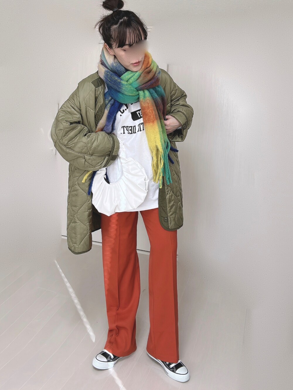 ホワイト系のTシャツ/カットソー、オレンジ系のスラックス、グリーン系のミリタリージャケットを着用したレディースの冬コーディネートの4枚目の写真