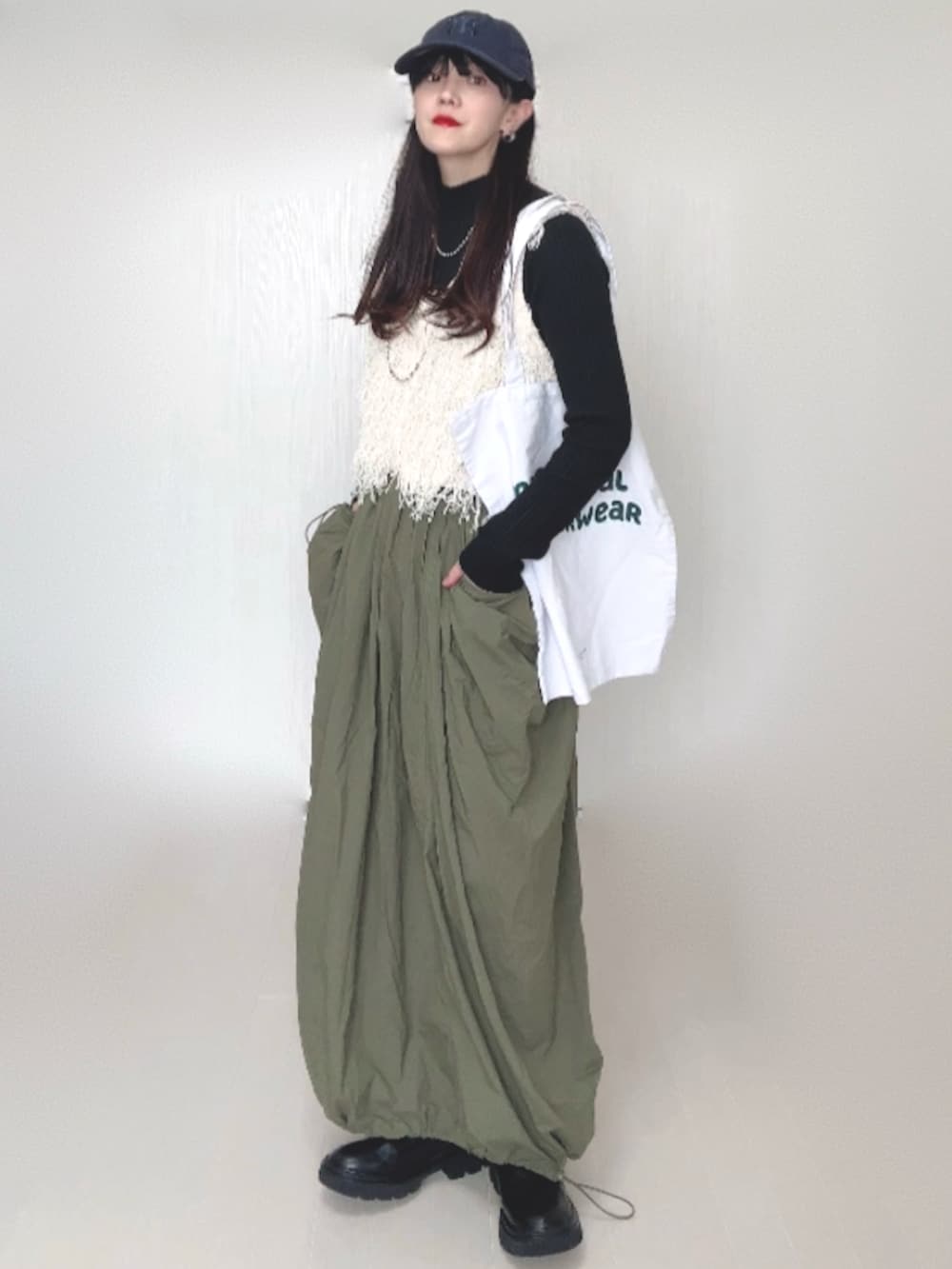 ホワイト系のベスト、ブラック系のニット/セーター、グリーン系のスカートを着用したレディースの秋コーディネートの4枚目の写真