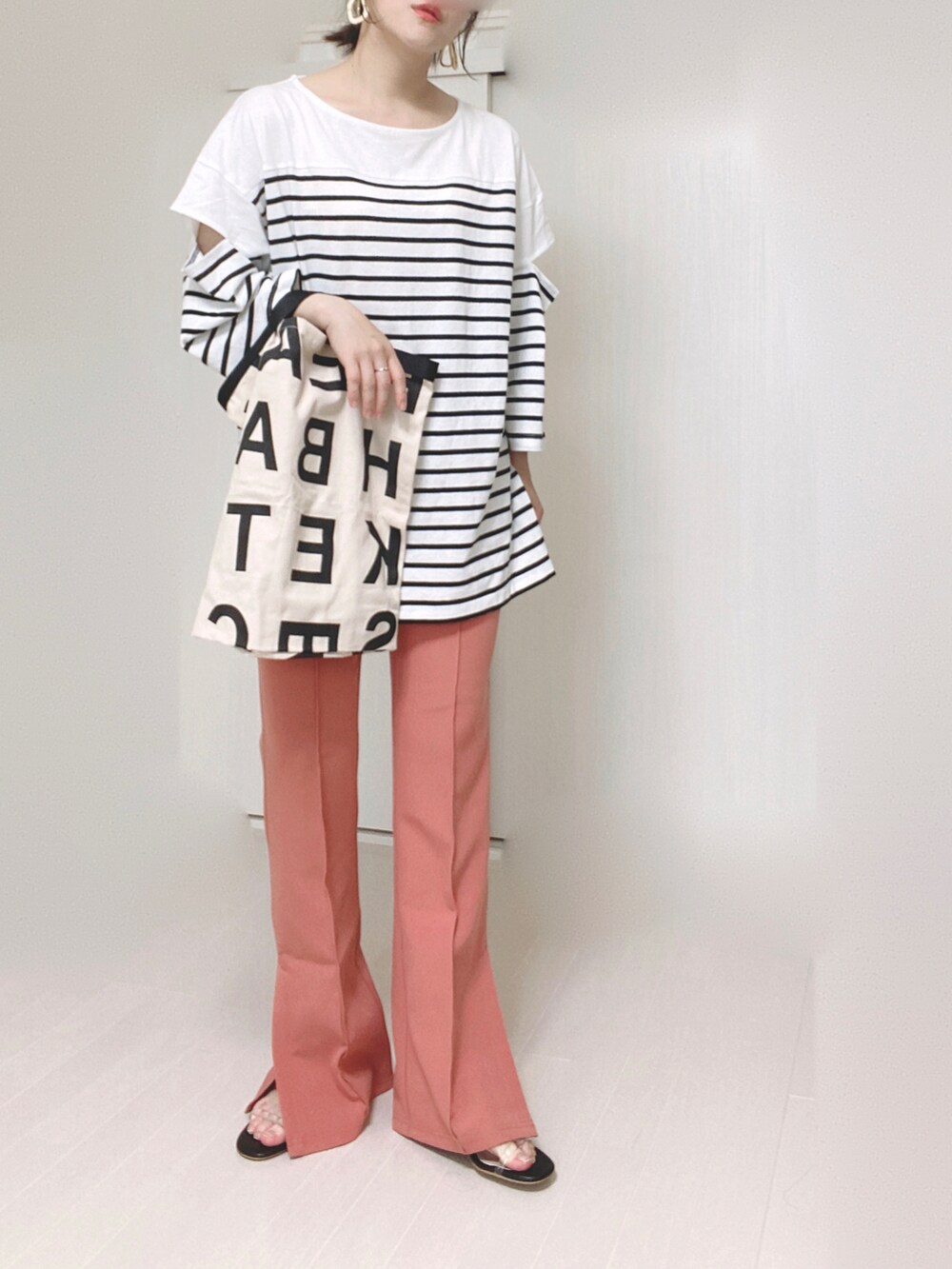 ピンク系のスラックス、ブラック系のTシャツ/カットソー、ホワイト系のトートバッグを着用したレディースの夏コーディネートの3枚目の写真