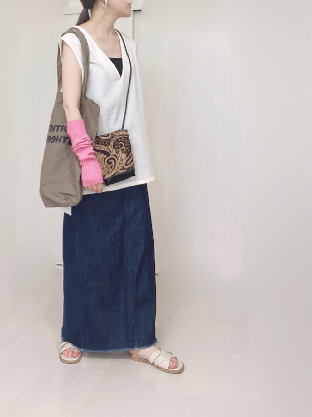 ブルー系のデニムスカート、ブラウン系のトートバッグ、ブラック系のショルダーバッグを着用したレディースの夏コーディネートの2枚目の写真